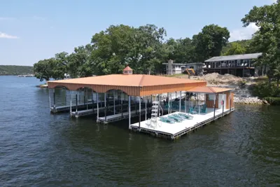 Covered dock with a copper-colored roof, boat slips and an open swim platform
