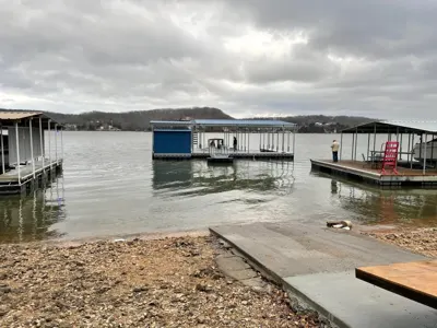 Covered docks and open boat slips beside a lakeside ramp
