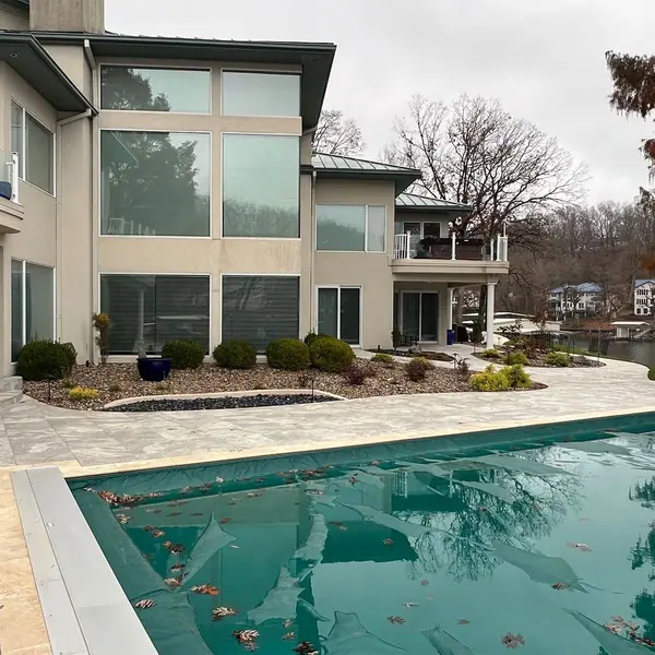 Landscaped lakefront yard with a stone path, planting beds and a pool beside the home