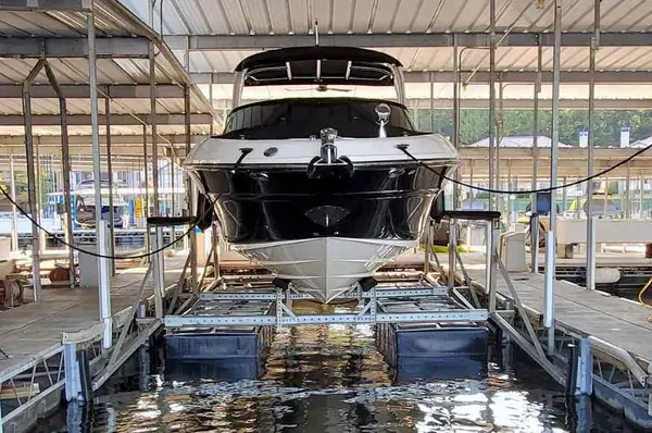 White motorboat raised on a LOTO Lift pneumatic boat lift inside a covered dock slip