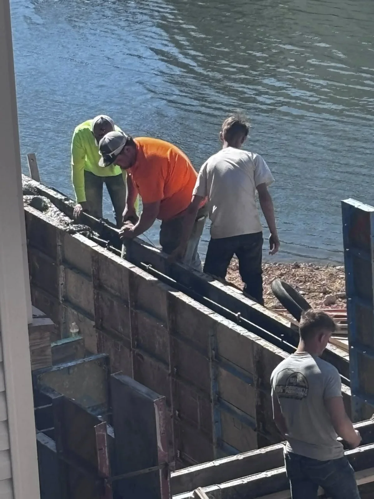 Concrete formwork and crew working along a waterfront seawall.